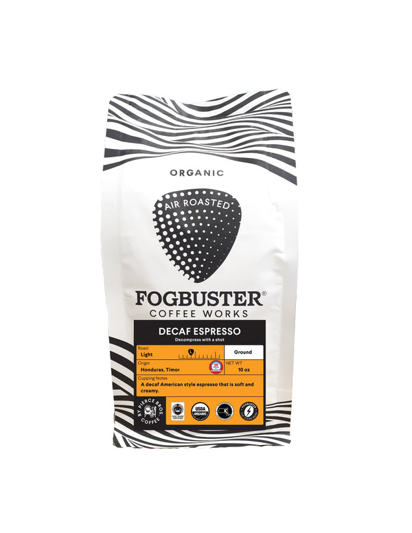 A white Fogbuster® Coffee Works Decaf Espresso bag with black zebra stripes, labeled "Organic" and "Air Roasted." Made with Honduras Timor beans, it offers a light espresso roast for a smooth, creamy decaf taste.