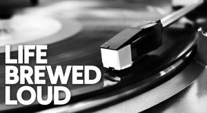 Close-up of a record player’s tonearm and stylus on a spinning vinyl record, with the words