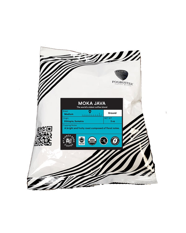 A 12 oz bag of Fogbuster® Coffee Works Moka Java, a fruity medium roast ground coffee from Ethiopia and Sumatra, featuring a black and white striped design, blue label with product details, and QR code.