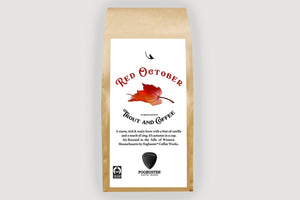 A brown paper bag labeled "Red October" by Trout & Coffee features a red autumn leaf, product description, and logos for fresh roasted coffee, Fair Trade, and Fogbuster Coffee Works.