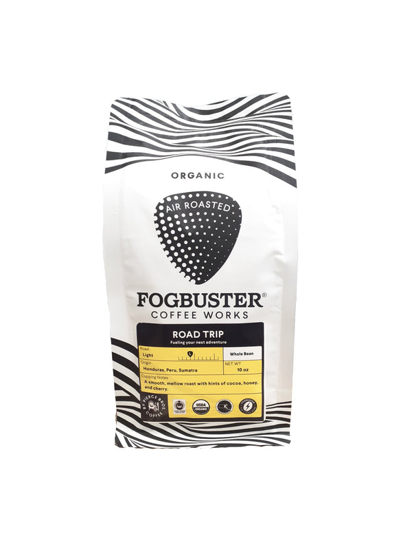 A white bag of Fogbuster® Coffee Works "Road Trip" organic air-roasted coffee, a smooth mellow roast with cocoa and honey notes, crafted from Honduras beans plus select Peru and Sumatra origins.