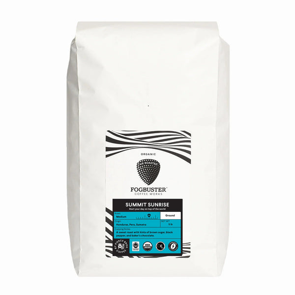 A white bag of Fogbuster® Coffee Works Summit Sunrise organic ground coffee features a black and white label with bittersweet notes, plus a blue section indicating it's medium roast and ground coffee.
