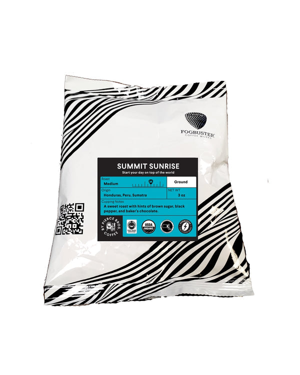 A white, zebra-patterned coffee bag labeled "Summit Sunrise" from Fogbuster® Coffee Works contains medium roast ground coffee with bittersweet flavor notes of brown sugar, black pepper, and baker’s chocolate.