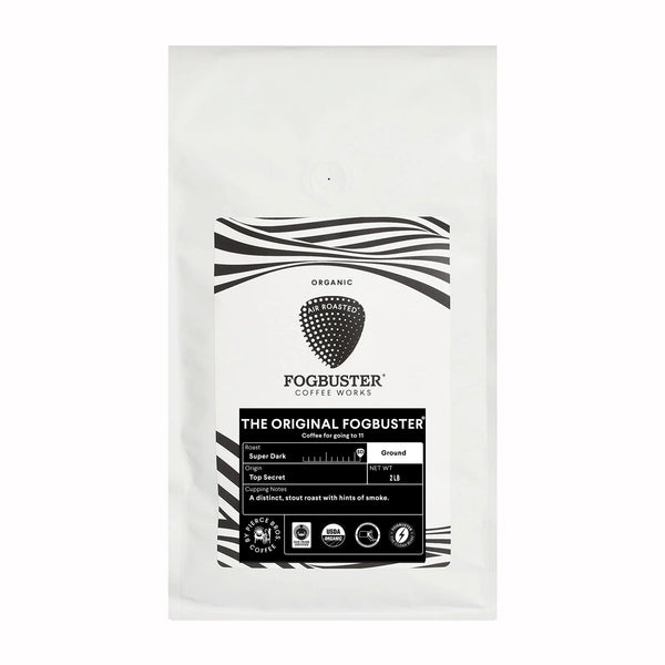 A white bag of Fogbuster® Coffee Works' The Original FogbusterⓇ organic ground coffee with a black and white label, stout roast tasting notes, and icons for USDA Organic and Non-GMO certification.