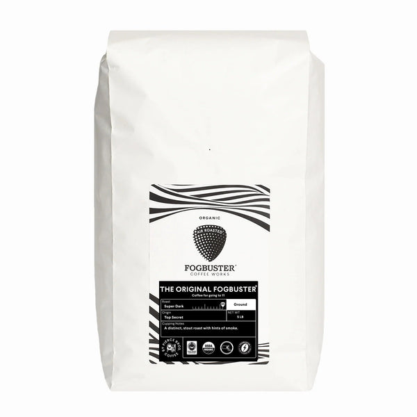 A white bag of Fogbuster® Coffee Works The Original FogbusterⓇ stout roast ground coffee with a black and white label, coffee bean graphics, product details, and cupping notes of rich smoke.