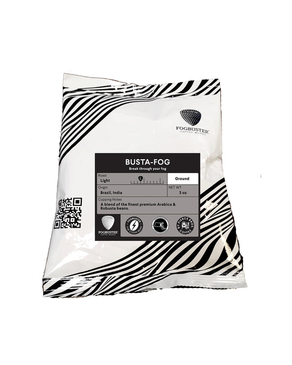 A white and black wavy coffee bag labeled "Wrecking Ball" from Fogbuster® Coffee Works highlights high caffeine, roast level, grind, Brazil and India origin, net weight (3 oz), QR code, and icons at the bottom.