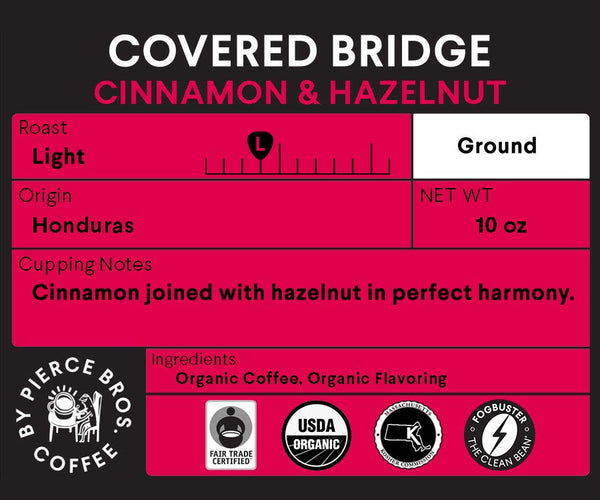 A label for Fogbuster® Coffee Works Covered Bridge light roast cinnamon hazelnut coffee, 10 oz, featuring organic and fair trade certifications and showcasing a smooth blend of cinnamon and hazelnut in premium Honduras coffee.
