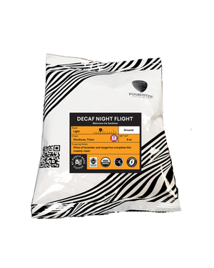 A 3oz ground decaf sample, Decaf Night Flight by Fogbuster® Coffee Works, in a white and black striped bag. This light roast Honduras coffee features notes of lavender and tangerine with certification logos on the front.