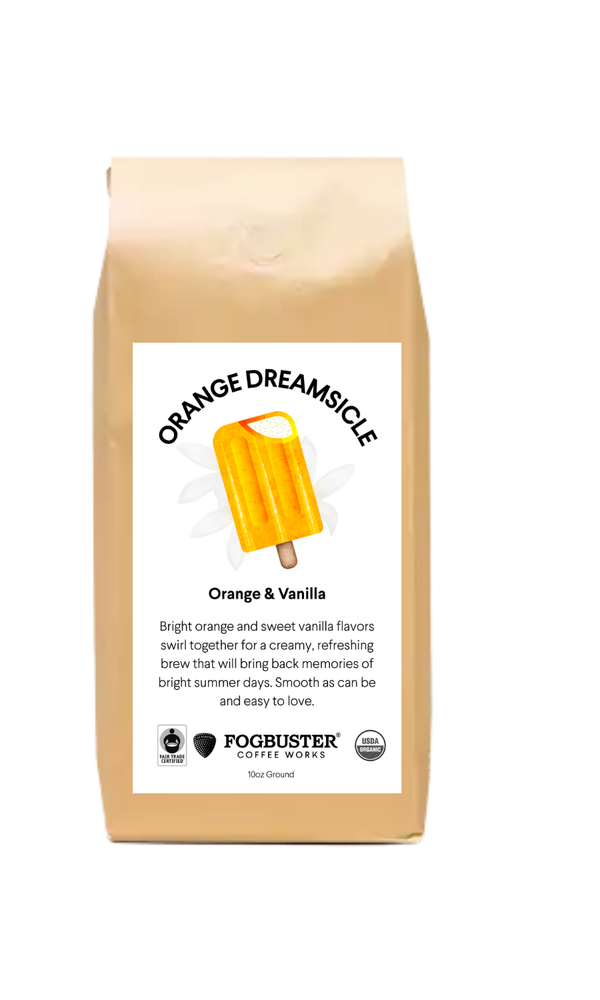 A tan Fogbuster® Coffee Works bag labeled "Orange Dreamsicle" shows an orange popsicle and describes the 9oz ground light roast coffee’s orange and vanilla flavor.