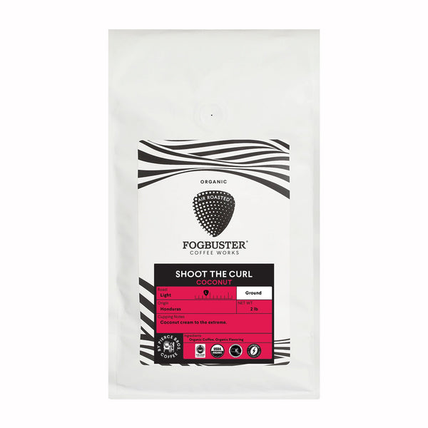 The product is a 2 lb white coffee bag with black and pink accents, labeled with "Fogbuster® Coffee Works" and "Fundraiser - Shoot The Curl (Coconut coffee)." It prominently features the word "Organic" to emphasize the premium quality of its shade-grown beans. The design is accented by wavy black lines at the top of the packaging.