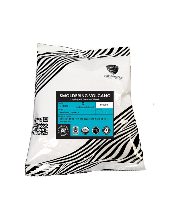 A white coffee bag with abstract black stripes, labeled "Titanic: The Blend" by Fogbuster® Coffee Works. The label indicates medium roast, ground coffee with tasting notes of dried fruit and sugarcane. This Organic Fair Trade coffee comes with a QR code and has a net weight of 12 oz.