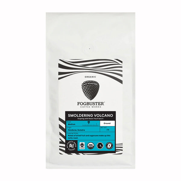 A white bag of Fogbuster® Coffee Works' Titanic: The Blend medium roast Organic Fair Trade coffee. The label displays the brand logo, coffee name, and details including the origin (India, Sumatra), flavor notes (certified fruit and sugarcane), and whether it is available ground or whole.