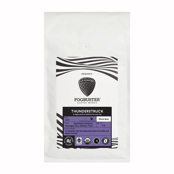 White coffee bag labeled "Thunderstruck" by Fogbuster® Coffee Works. It features a purple and black design with text highlighting its origins from Guatemala, Honduras, Nicaragua, Peru, Sumatra, and Timor. This premium French roast coffee is shade-grown and offers an exquisite brew with notes of vanilla and licorice.